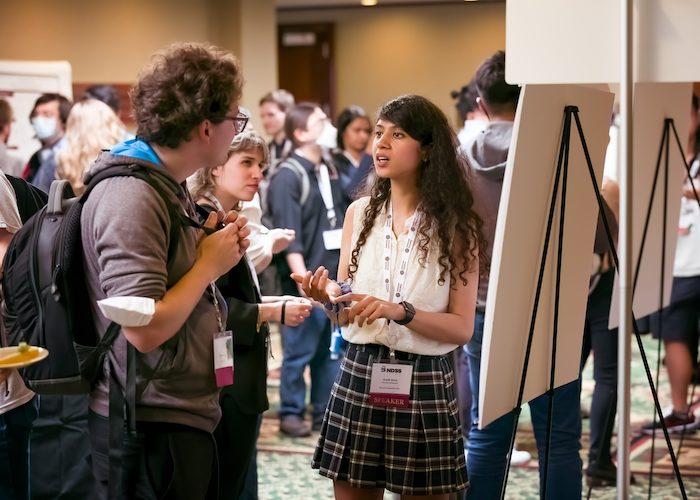 a woman stands in front of whiteboard and talks to a man and a woman