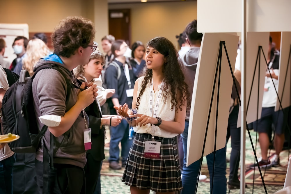 a woman stands in front of whiteboard and talks to a man and a woman